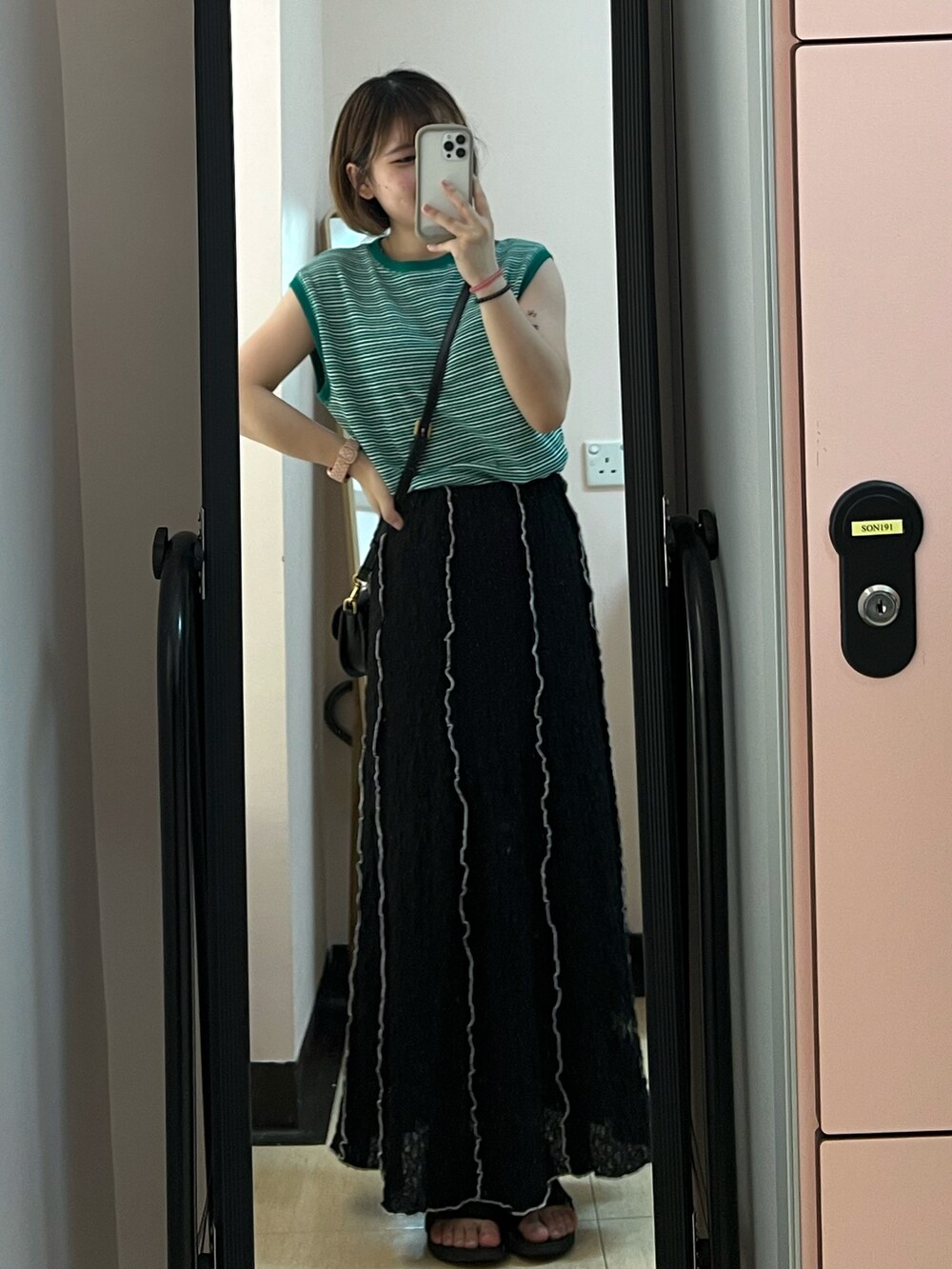 ホワイト系のサンダル、ブラック系のスカート、ブラック系のショルダーバッグを着用したレディースの夏コーディネートの2枚目の写真