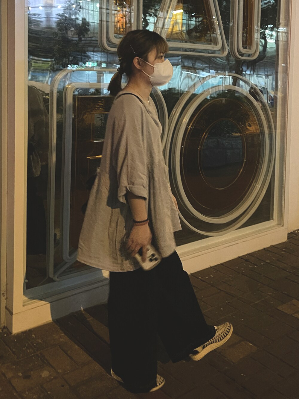 ブラック系のパンツ、グレー系のトップス、ホワイト系のサンダルを着用したレディースの春コーディネートの2枚目の写真