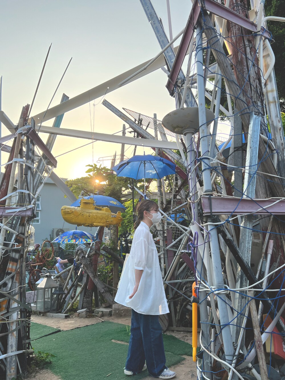 ホワイト系のトップス、グリーン系のタンクトップ、ブルー系のデニムパンツを着用したレディースの春コーディネートの3枚目の写真