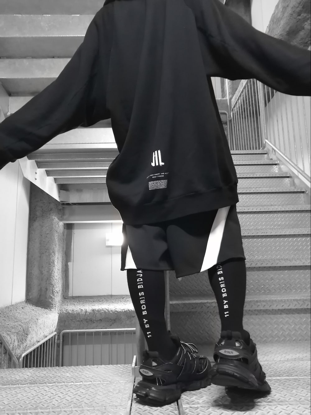 ブラック系のパーカー、ブラック系のパンツ、ブラック系のスニーカーを着用したメンズの春コーディネートの5枚目の写真