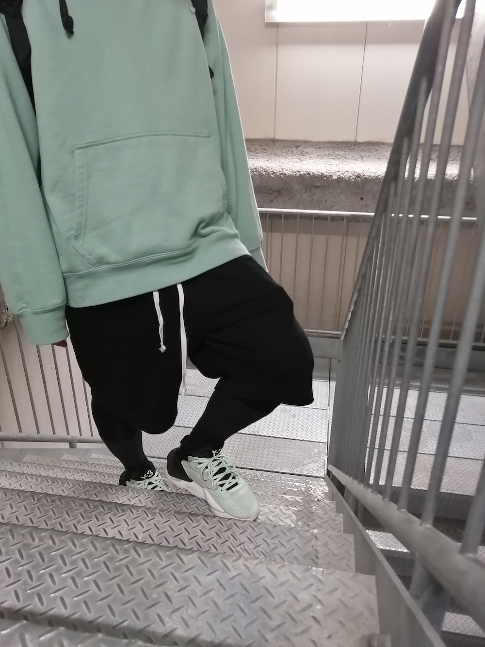 グリーン系のスニーカー、ブラック系のパンツ、グリーン系のパーカーを着用したメンズの春コーディネートの5枚目の写真