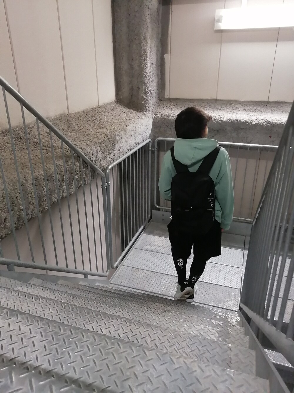 グリーン系のスニーカー、ブラック系のパンツ、グリーン系のパーカーを着用したメンズの春コーディネートの2枚目の写真