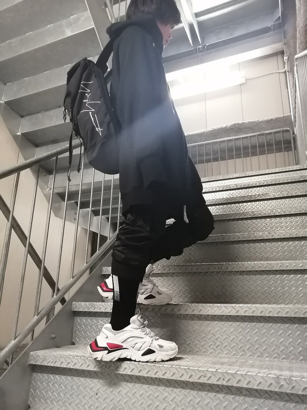 ホワイト系のスニーカー、ブラック系のカーゴパンツ、ブラック系のパーカーを着用したメンズの春コーディネートの3枚目の写真