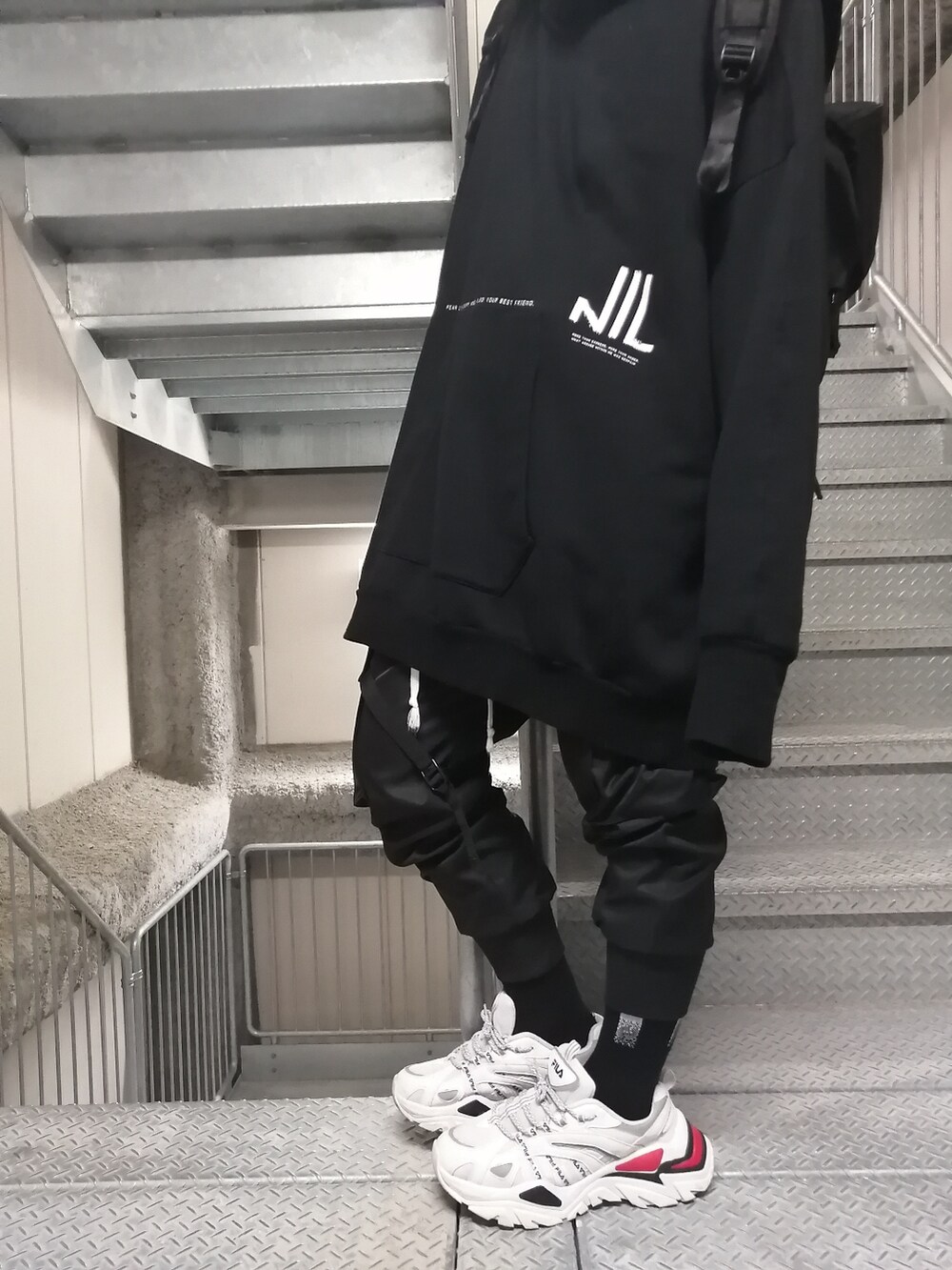ホワイト系のスニーカー、ブラック系のカーゴパンツ、ブラック系のパーカーを着用したメンズの春コーディネートの5枚目の写真