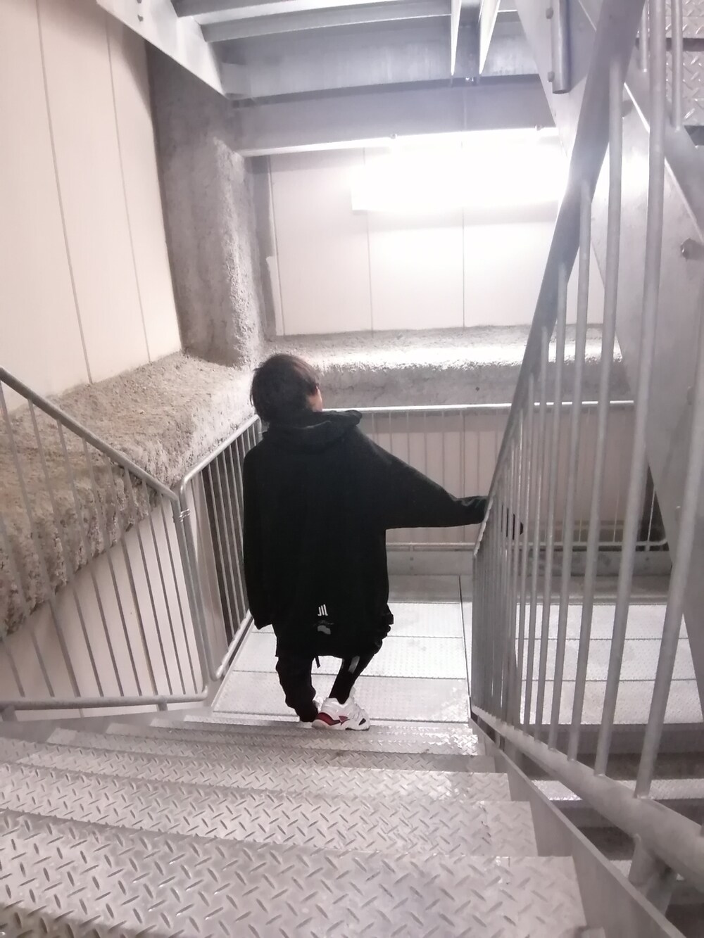 ホワイト系のスニーカー、ブラック系のカーゴパンツ、ブラック系のパーカーを着用したメンズの春コーディネートの4枚目の写真