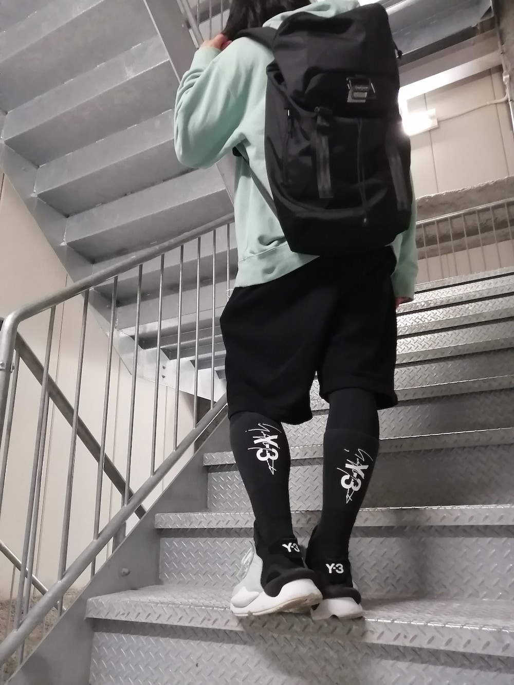 グリーン系のスニーカー、ブラック系のパンツ、グリーン系のパーカーを着用したメンズの春コーディネートの4枚目の写真