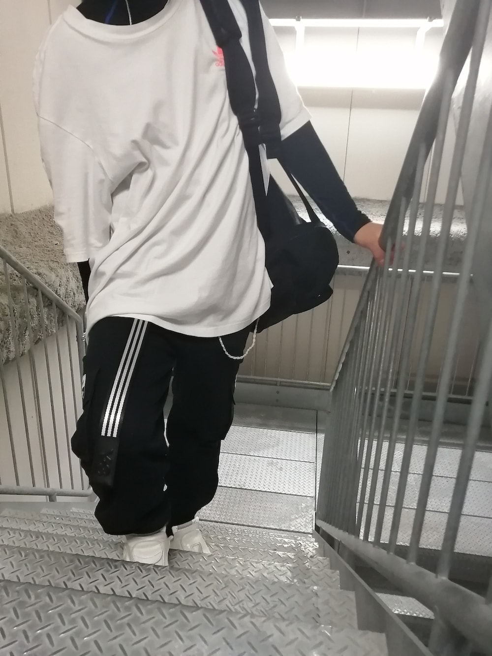 ホワイト系のスニーカー、ブラック系のカーゴパンツ、ホワイト系のトップスを着用したメンズの春コーディネートの5枚目の写真