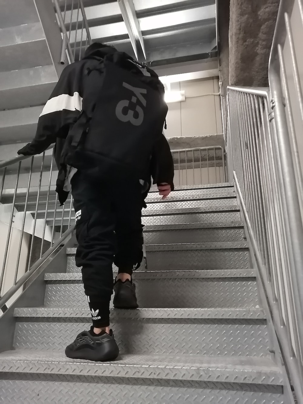 ブラック系のカーゴパンツ、ブラック系のスニーカー、ブラック系のバックパック/リュックを着用したメンズの春コーディネートの2枚目の写真