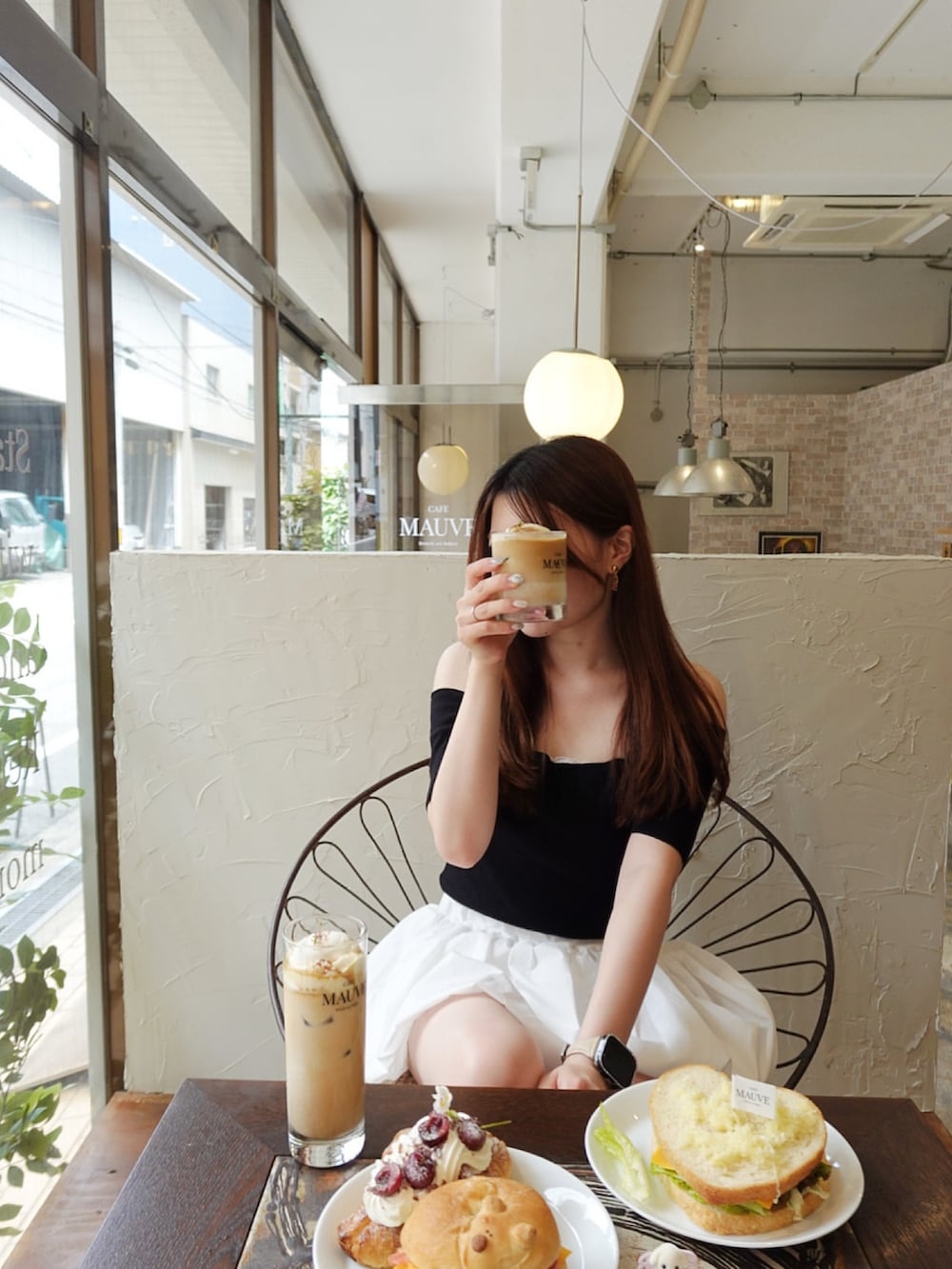 ホワイト系のスニーカー、ブラック系のトップス、ホワイト系のスカートを着用したレディースの夏コーディネートの4枚目の写真