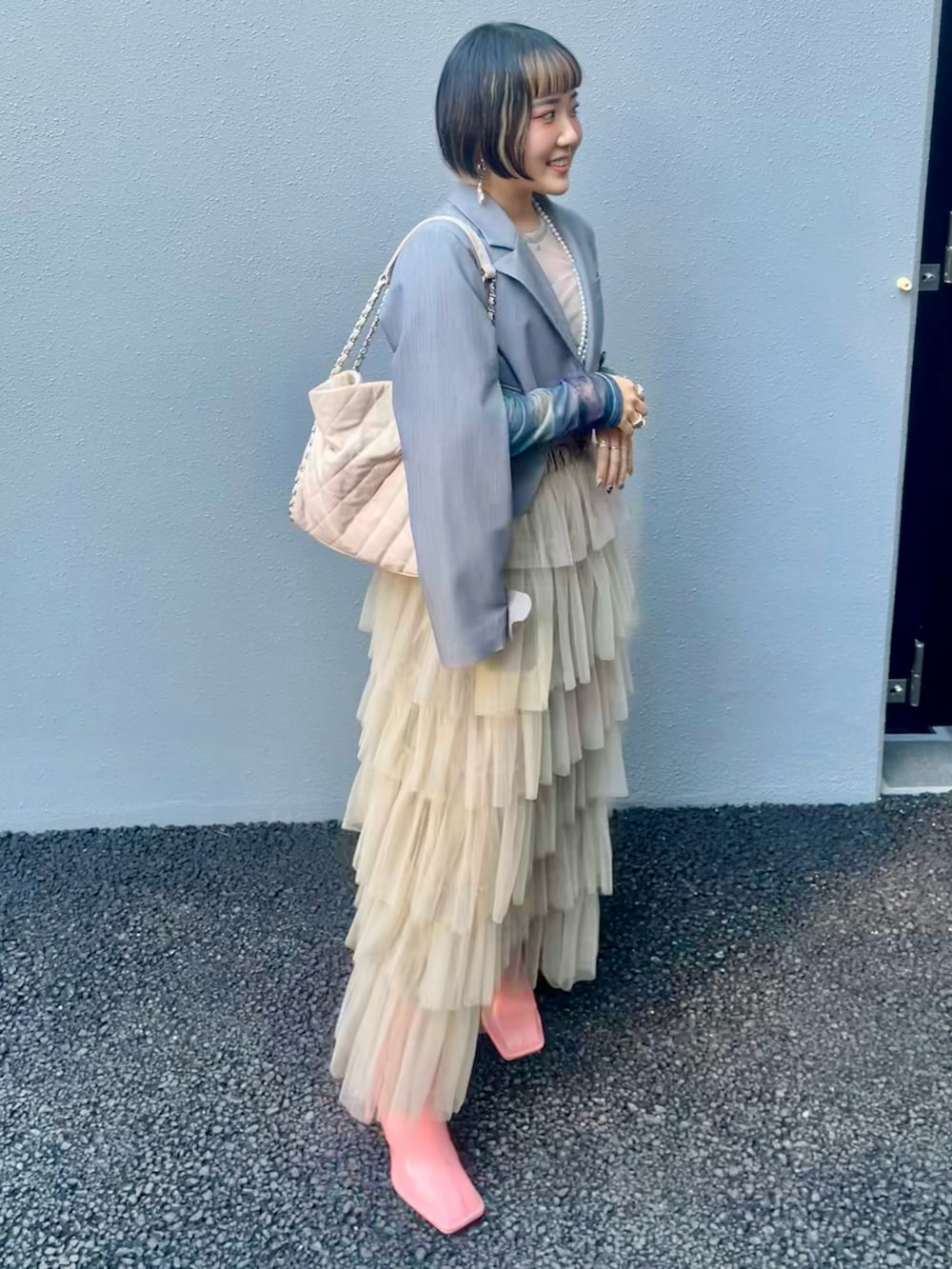 ベージュ系のスカート、ピンク系のブーツ、グレー系のその他アウターを着用したレディースの秋コーディネートの4枚目の写真