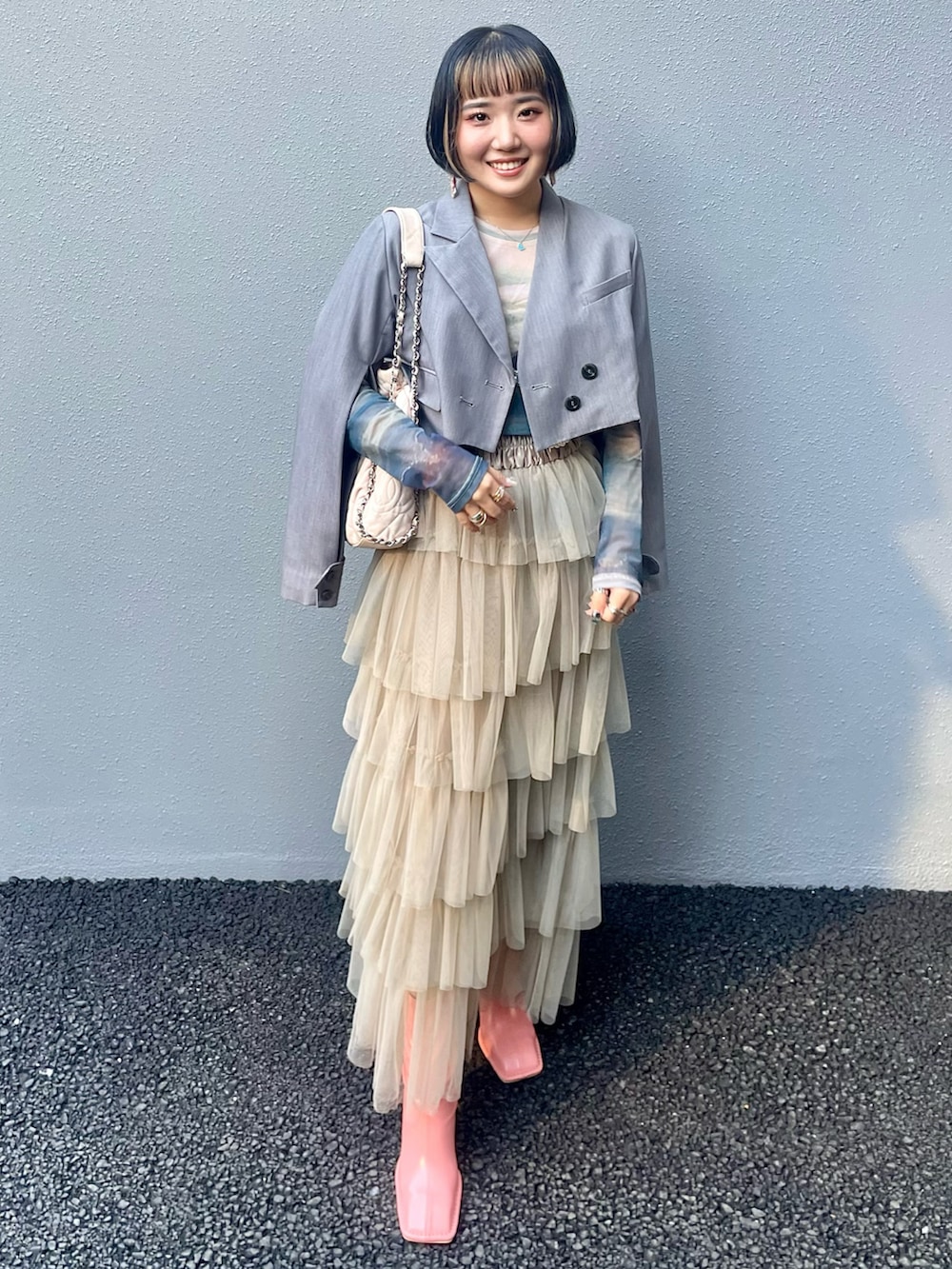 ベージュ系のスカート、ピンク系のブーツ、グレー系のその他アウターを着用したレディースの秋コーディネートの3枚目の写真