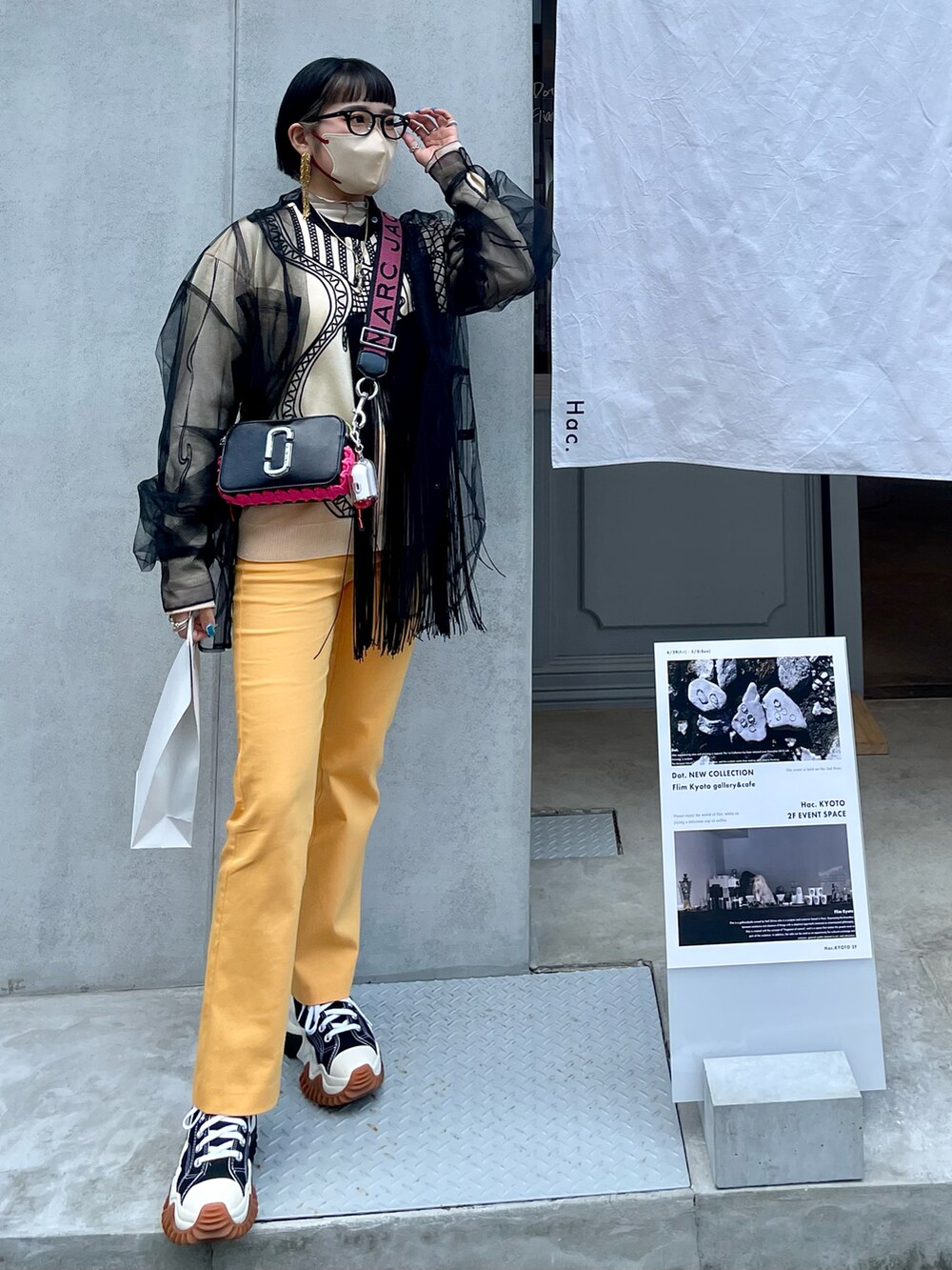 ブラック系のショルダーバッグ、オレンジ系のスラックス、ブラック系のスニーカーを着用したレディースの春コーディネートの3枚目の写真