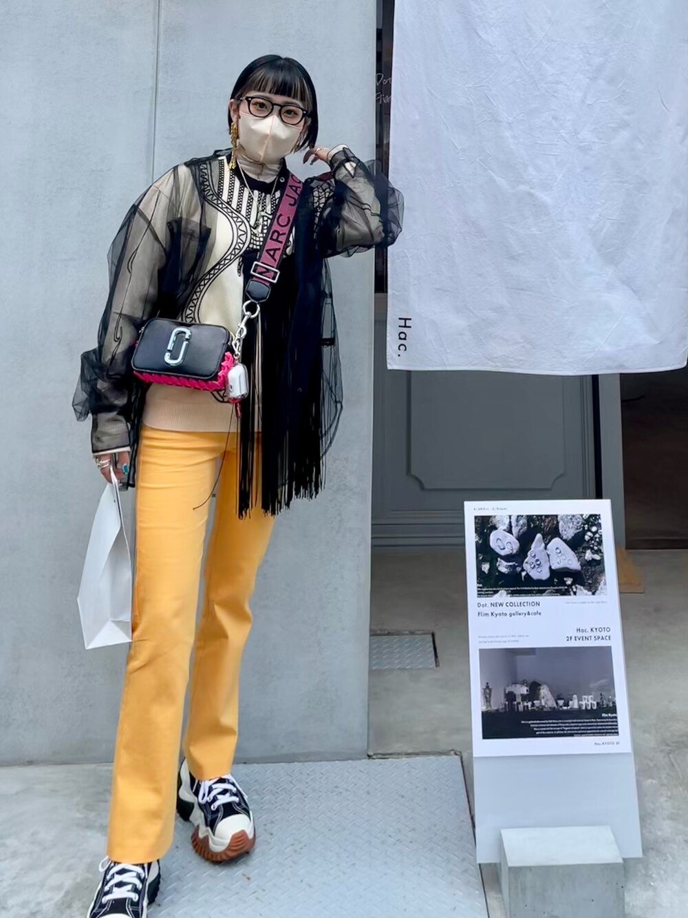 ブラック系のショルダーバッグ、オレンジ系のスラックス、ブラック系のスニーカーを着用したレディースの春コーディネートの4枚目の写真