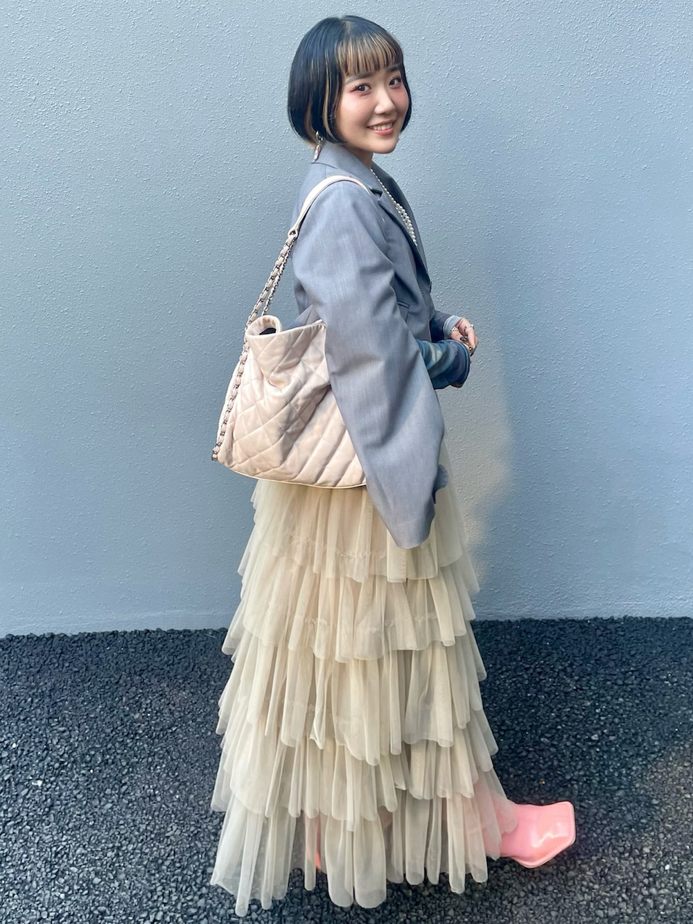 ベージュ系のスカート、ピンク系のブーツ、グレー系のその他アウターを着用したレディースの秋コーディネートの5枚目の写真