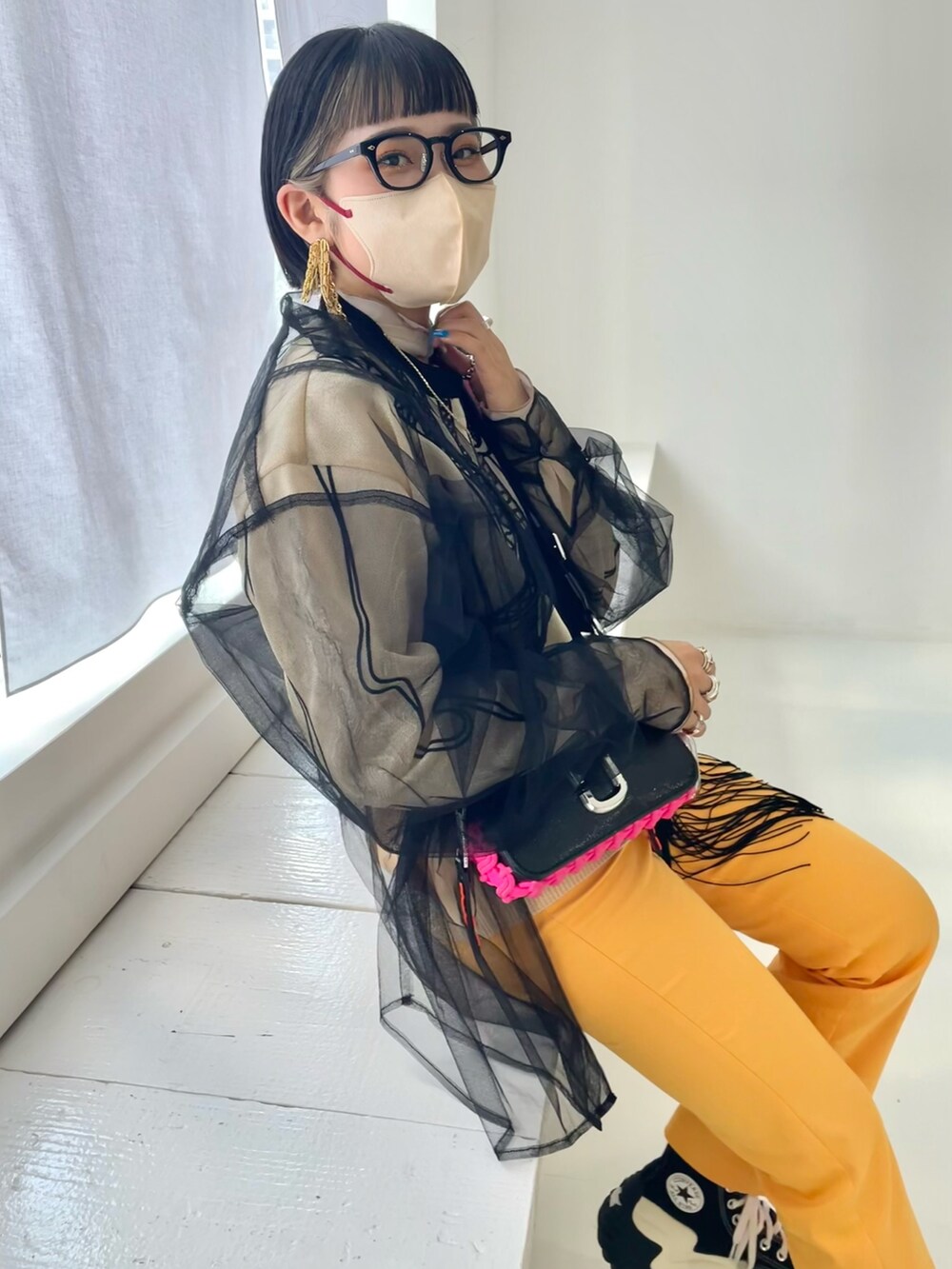 ブラック系のショルダーバッグ、オレンジ系のスラックス、ブラック系のスニーカーを着用したレディースの春コーディネートの2枚目の写真