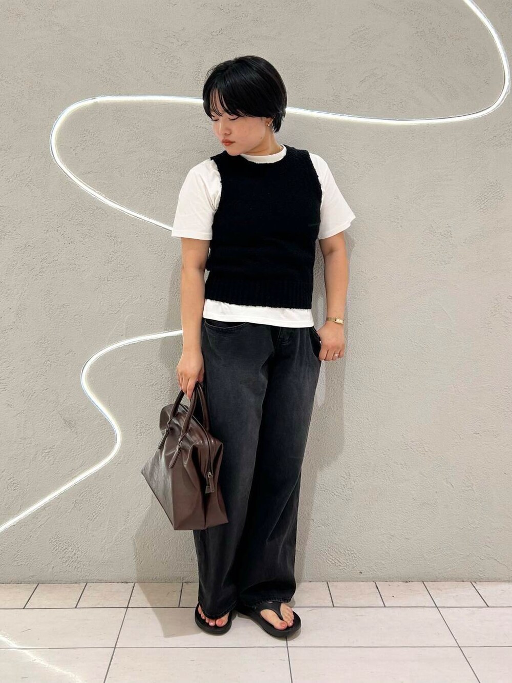 ブラック系のデニムパンツ、ホワイト系のTシャツ/カットソー、ブラック系のニット/セーターを着用したレディースの夏コーディネートの2枚目の写真