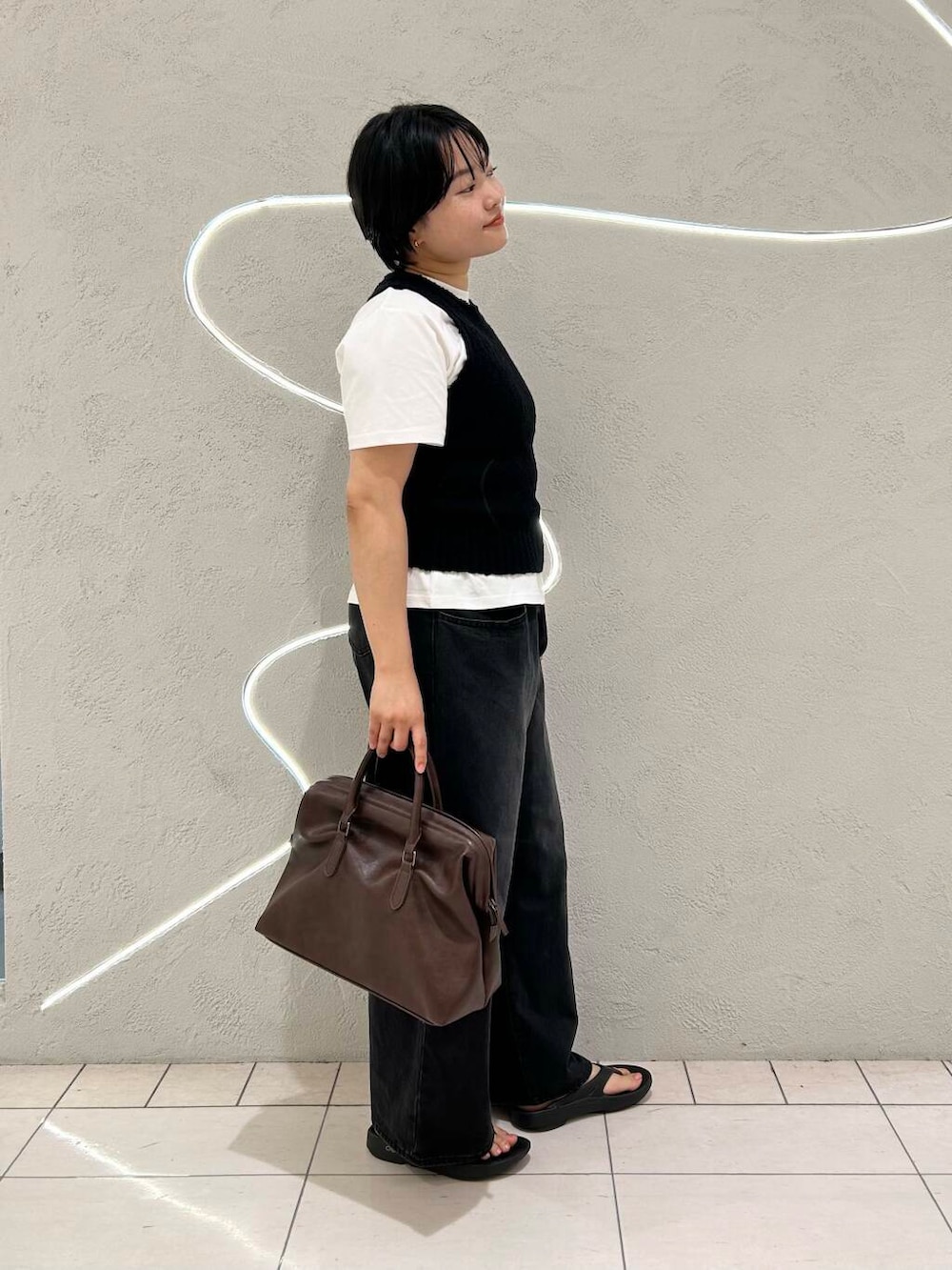 ブラック系のデニムパンツ、ホワイト系のTシャツ/カットソー、ブラック系のニット/セーターを着用したレディースの夏コーディネートの3枚目の写真