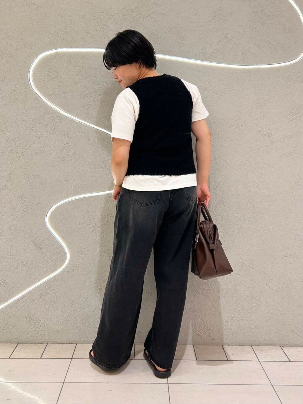 ブラック系のデニムパンツ、ホワイト系のTシャツ/カットソー、ブラック系のニット/セーターを着用したレディースの夏コーディネートの4枚目の写真