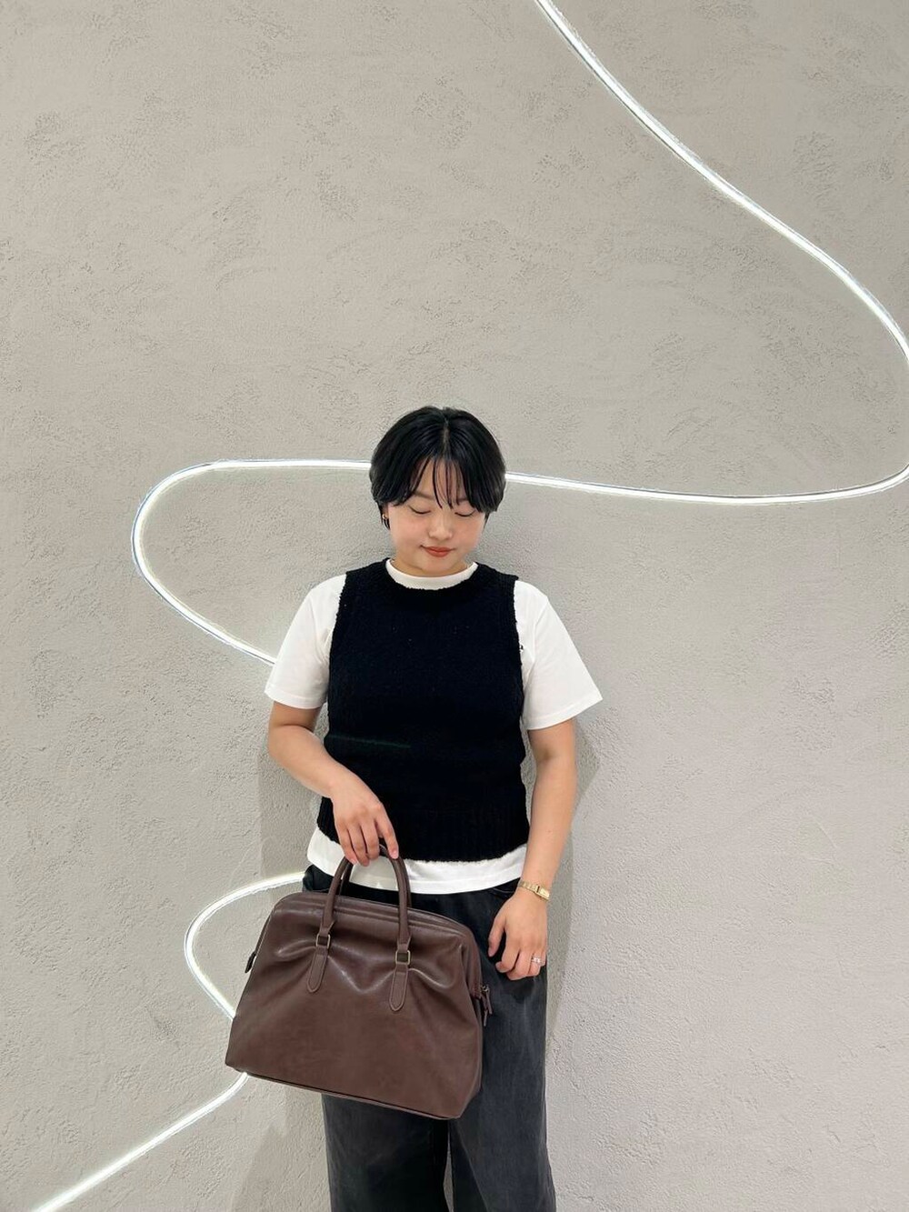 ブラック系のデニムパンツ、ホワイト系のTシャツ/カットソー、ブラック系のニット/セーターを着用したレディースの夏コーディネートの5枚目の写真