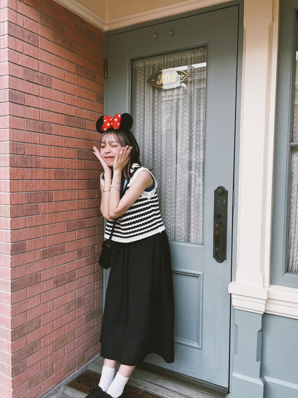 ブラウン系のショルダーバッグ、シルバー系のブレスレットを着用したレディースの夏コーディネートの3枚目の写真