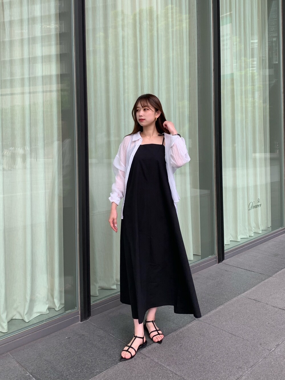 ブラック系のワンピース、ホワイト系のシャツ/ブラウス、ブラック系のサンダルを着用したレディースの夏コーディネートの2枚目の写真