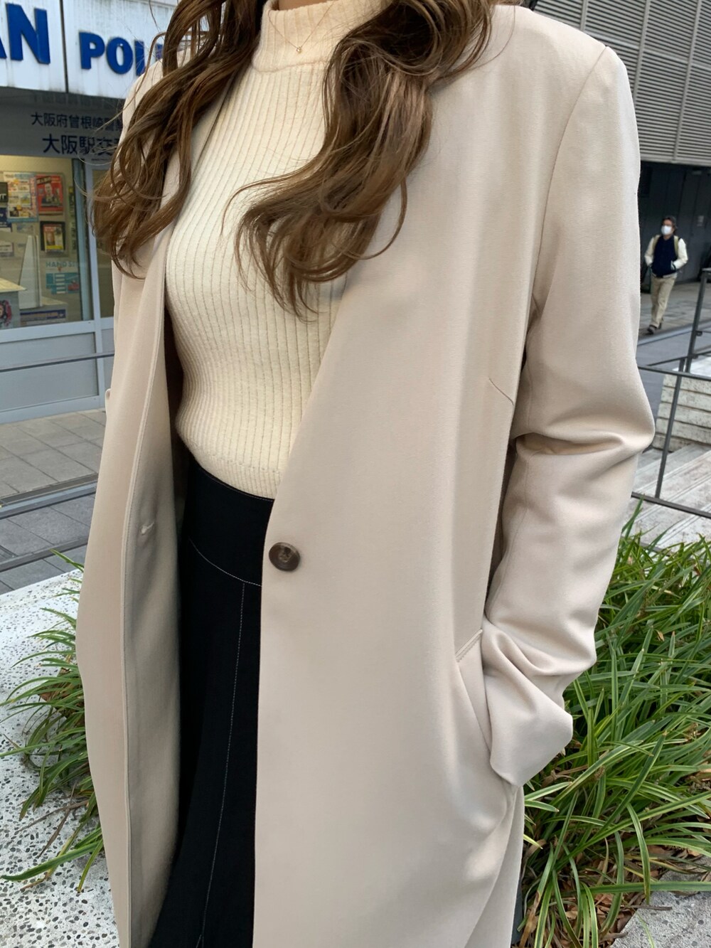 ブラック系のスカート、ホワイト系のニット/セーター、ベージュ系のノーカラーコートを着用したレディースの冬コーディネートの2枚目の写真