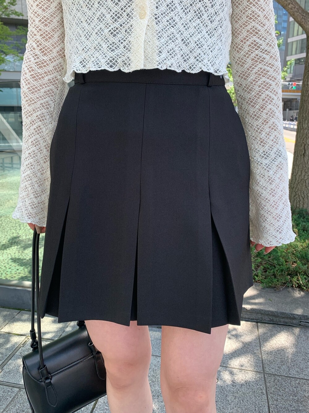 ブラック系のスカート、ブラック系のショルダーバッグを着用したレディースの夏コーディネートの3枚目の写真