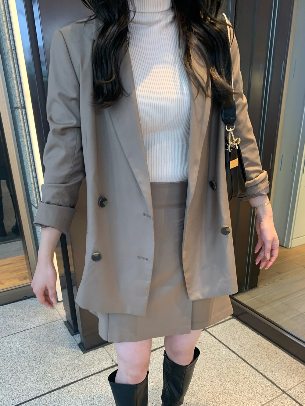 ブラウン系のテーラードジャケット、ブラウン系のスカート、ホワイト系のニット/セーターを着用したレディースの秋コーディネートの3枚目の写真