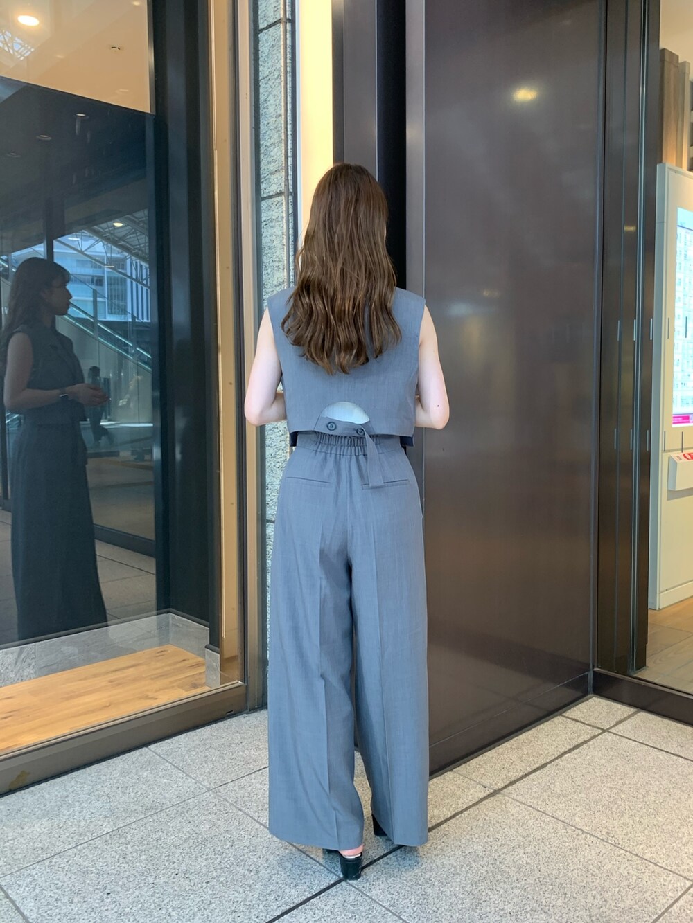 グレー系のスラックス、ブラック系のパンプス、グレー系のテーラードジャケットを着用したレディースの夏コーディネートの2枚目の写真