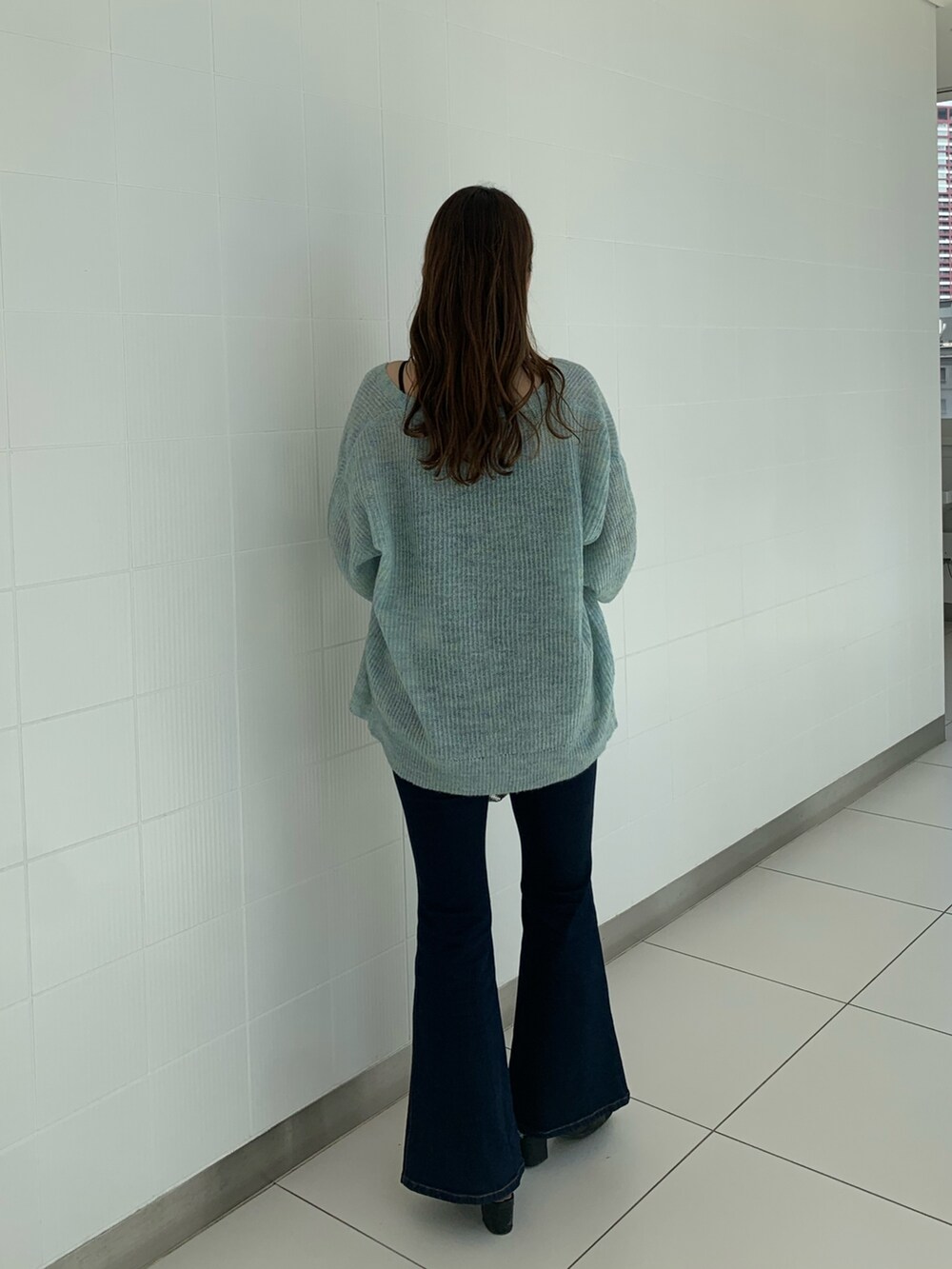 ブルー系のデニムパンツ、ブルー系のカーディガン/ボレロ、シルバー系のショルダーバッグを着用したレディースの秋コーディネートの2枚目の写真