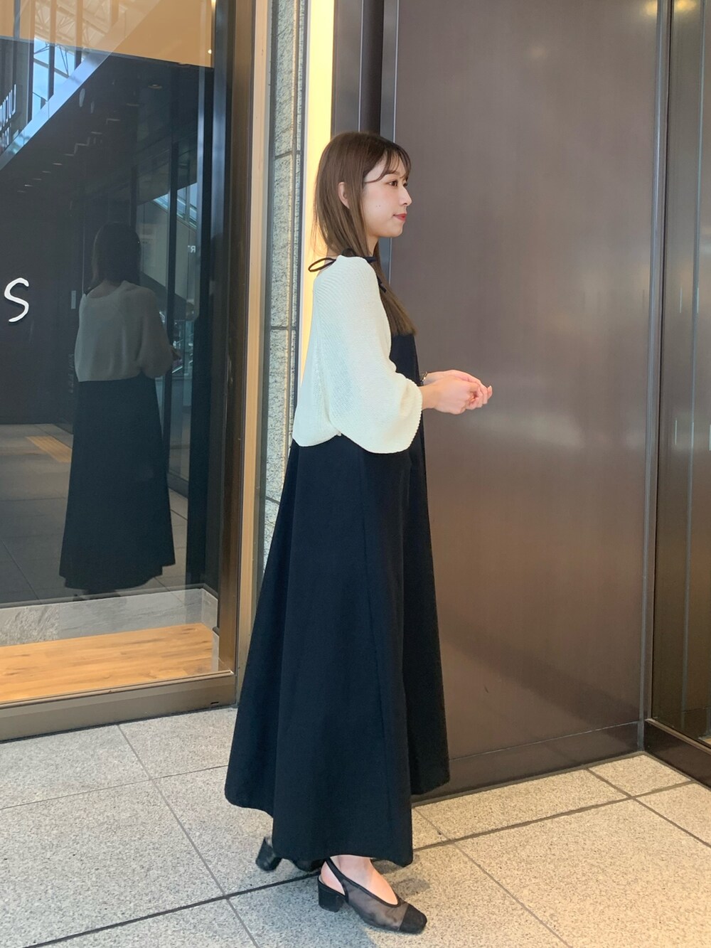 ブラック系のワンピース、ホワイト系のカーディガン/ボレロ、ブラック系のパンプスを着用したレディースの夏コーディネートの2枚目の写真