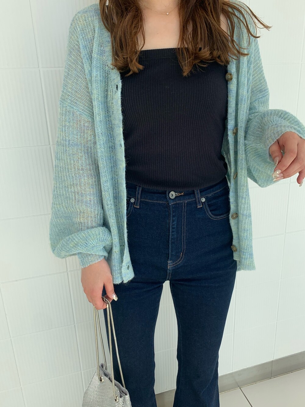 ブルー系のデニムパンツ、ブルー系のカーディガン/ボレロ、シルバー系のショルダーバッグを着用したレディースの秋コーディネートの3枚目の写真