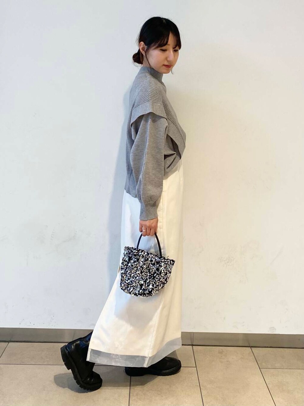 ブラック系のブーツ、グレー系のニット/セーター、ホワイト系のスカートを着用したレディースの冬コーディネートの3枚目の写真