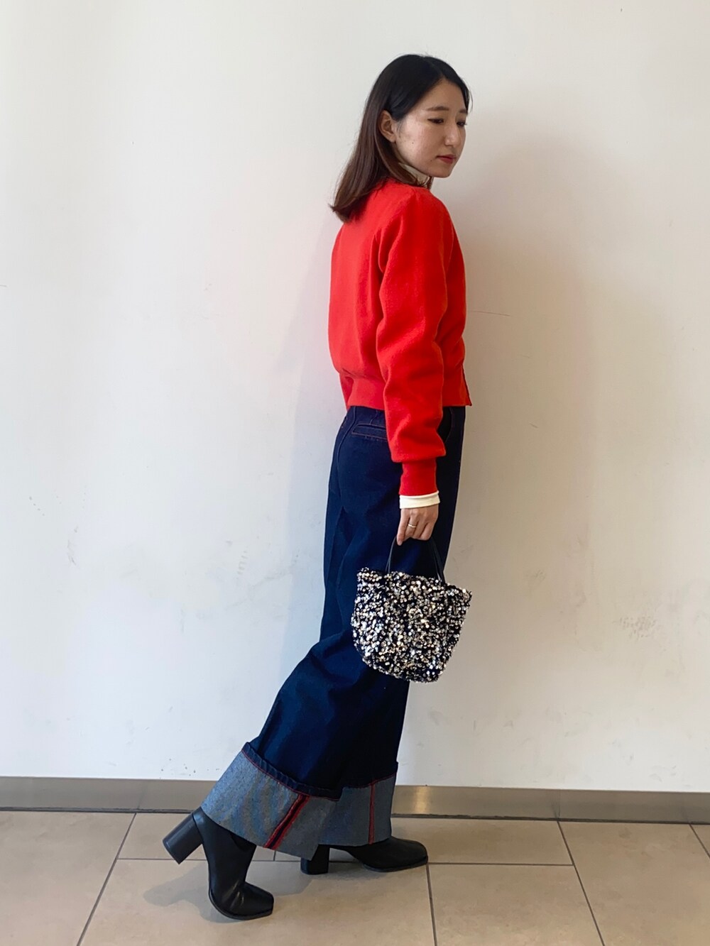 レッド系のカーディガン/ボレロ、ホワイト系のTシャツ/カットソー、ブルー系のデニムパンツを着用したレディースの冬コーディネートの2枚目の写真