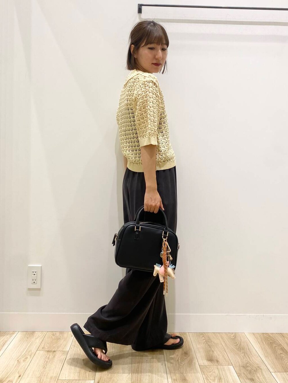 ブラック系のボストンバッグ、ベージュ系のニット/セーター、ブラウン系のその他パンツを着用したレディースの夏コーディネートの2枚目の写真