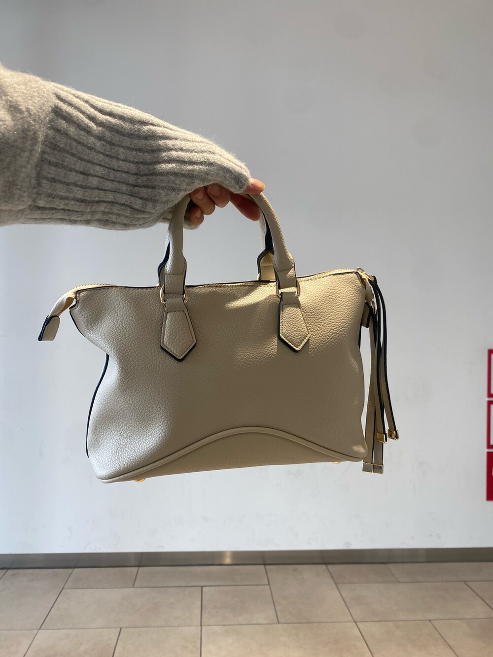 ホワイト系のボストンバッグ、ブラック系のブーツ、グレー系のワンピースを着用したレディースの冬コーディネートの3枚目の写真