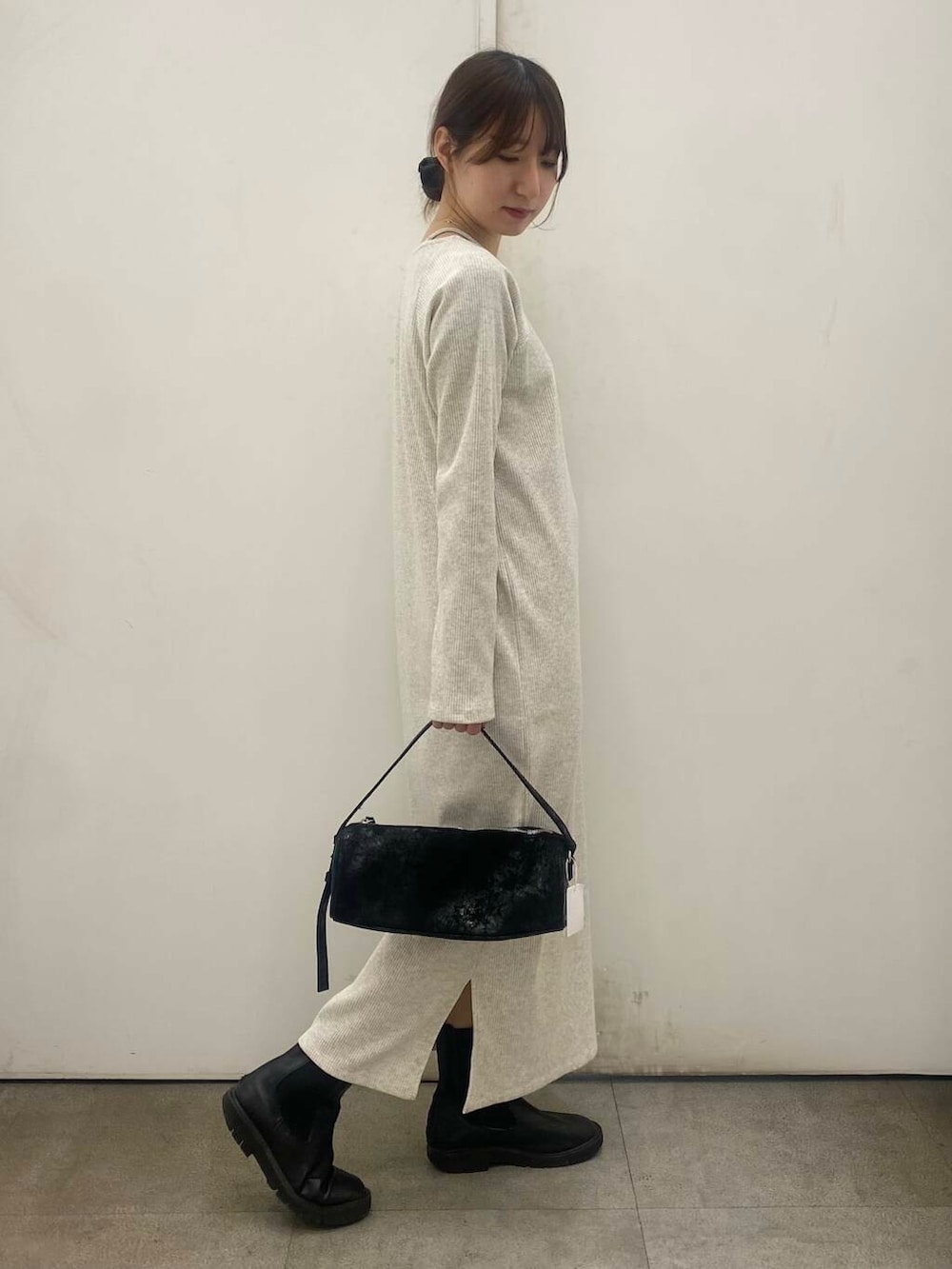 ブラック系のブーツ、ベージュ系のワンピース、ブラック系のハンドバッグを着用したレディースの冬コーディネートの2枚目の写真