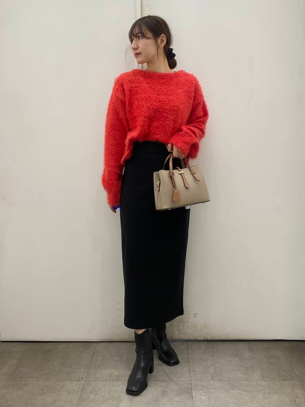 ベージュ系のハンドバッグ、ブラック系のブーツ、レッド系のニット/セーターを着用したレディースの冬コーディネートの2枚目の写真