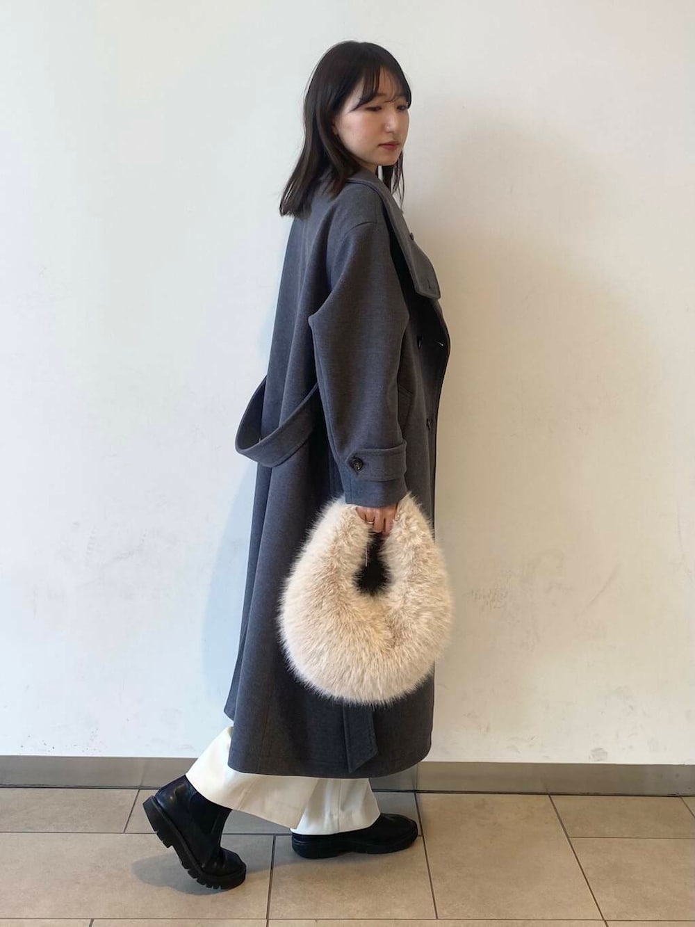 ベージュ系のハンドバッグ、ブラック系のブーツ、グレー系のその他アウターを着用したレディースの冬コーディネートの4枚目の写真