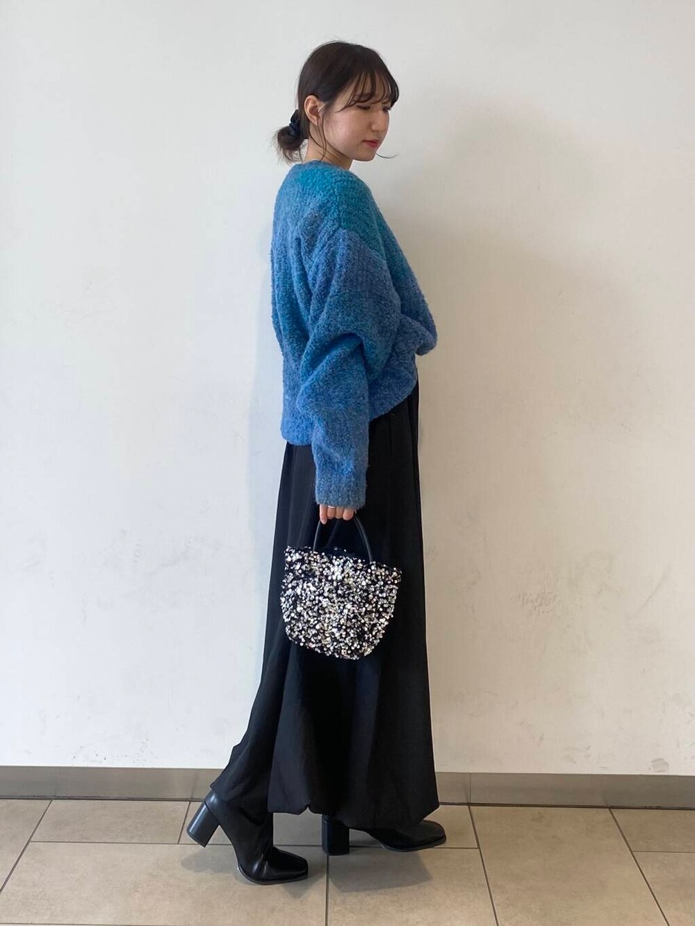 ブラック系のスカート、シルバー系のショルダーバッグ、ブラック系のブーツを着用したレディースの冬コーディネートの2枚目の写真