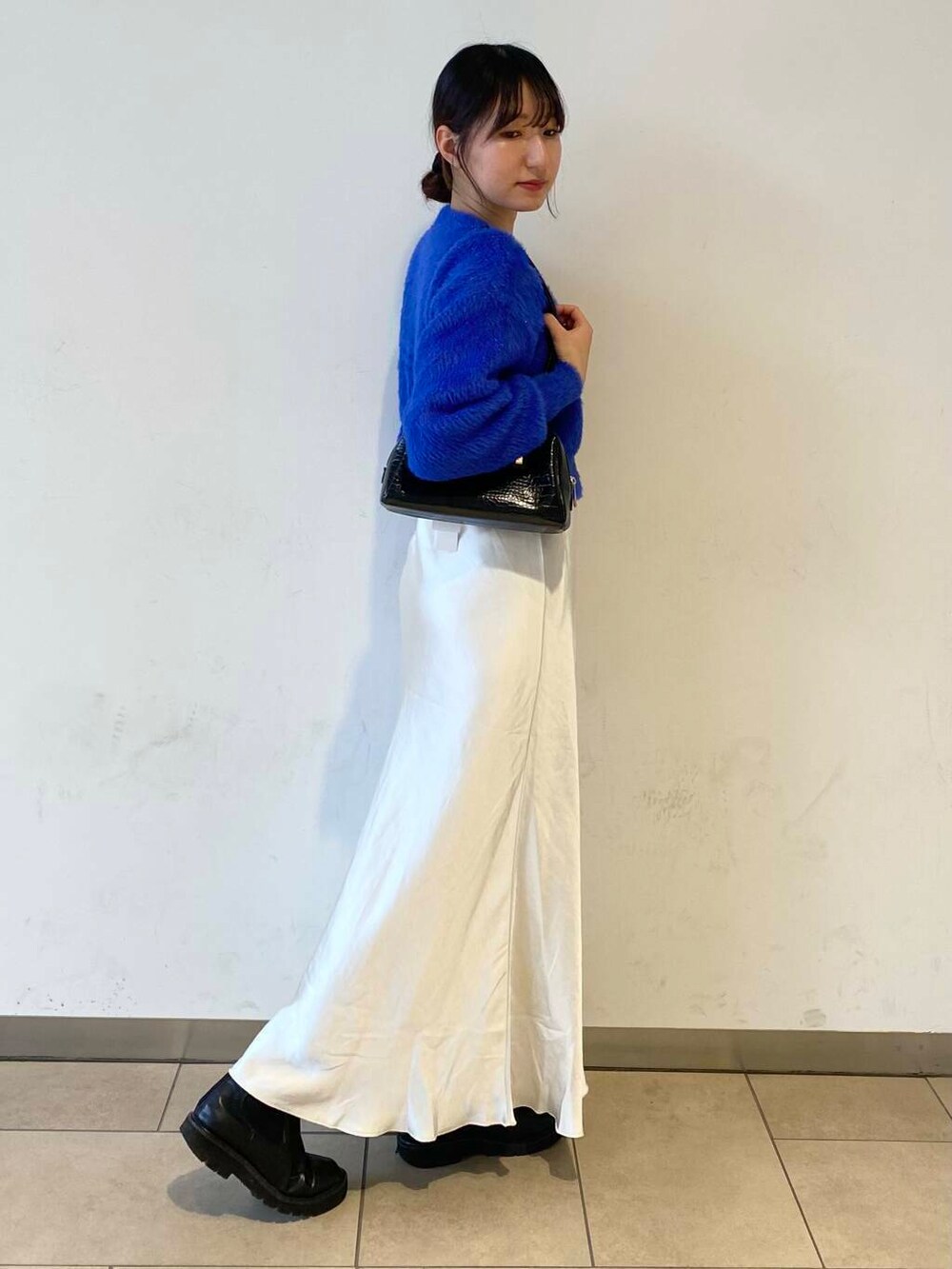 ブルー系のカーディガン/ボレロ、ブラック系のブーツ、ホワイト系のスカートを着用したレディースの冬コーディネートの3枚目の写真
