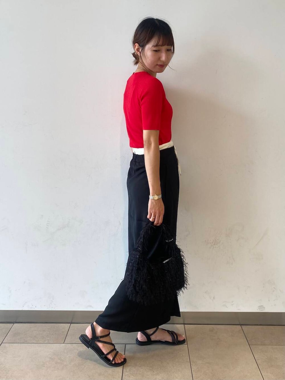 レッド系のニット/セーター、ブラック系のスカートを着用したレディースの夏コーディネートの2枚目の写真