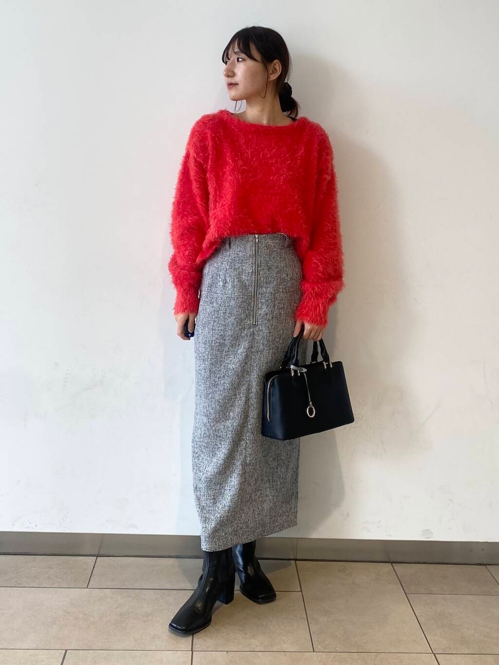 ブラック系のブーツ、ブラック系のハンドバッグ、レッド系のニット/セーターを着用したレディースの冬コーディネートの2枚目の写真