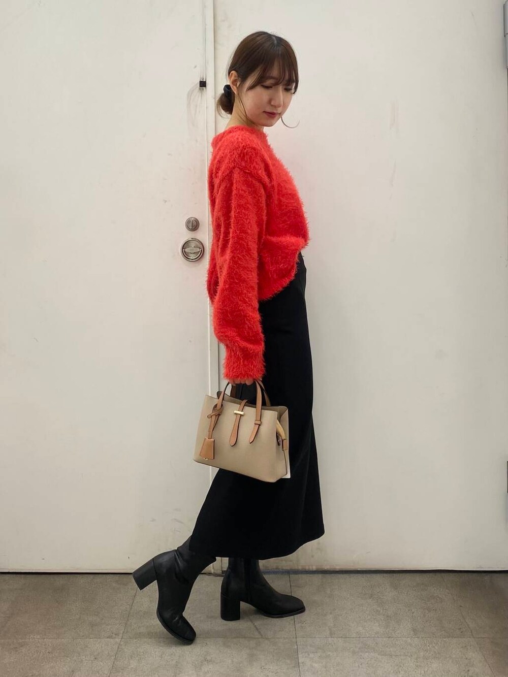ベージュ系のハンドバッグ、ブラック系のブーツ、レッド系のニット/セーターを着用したレディースの冬コーディネートの3枚目の写真