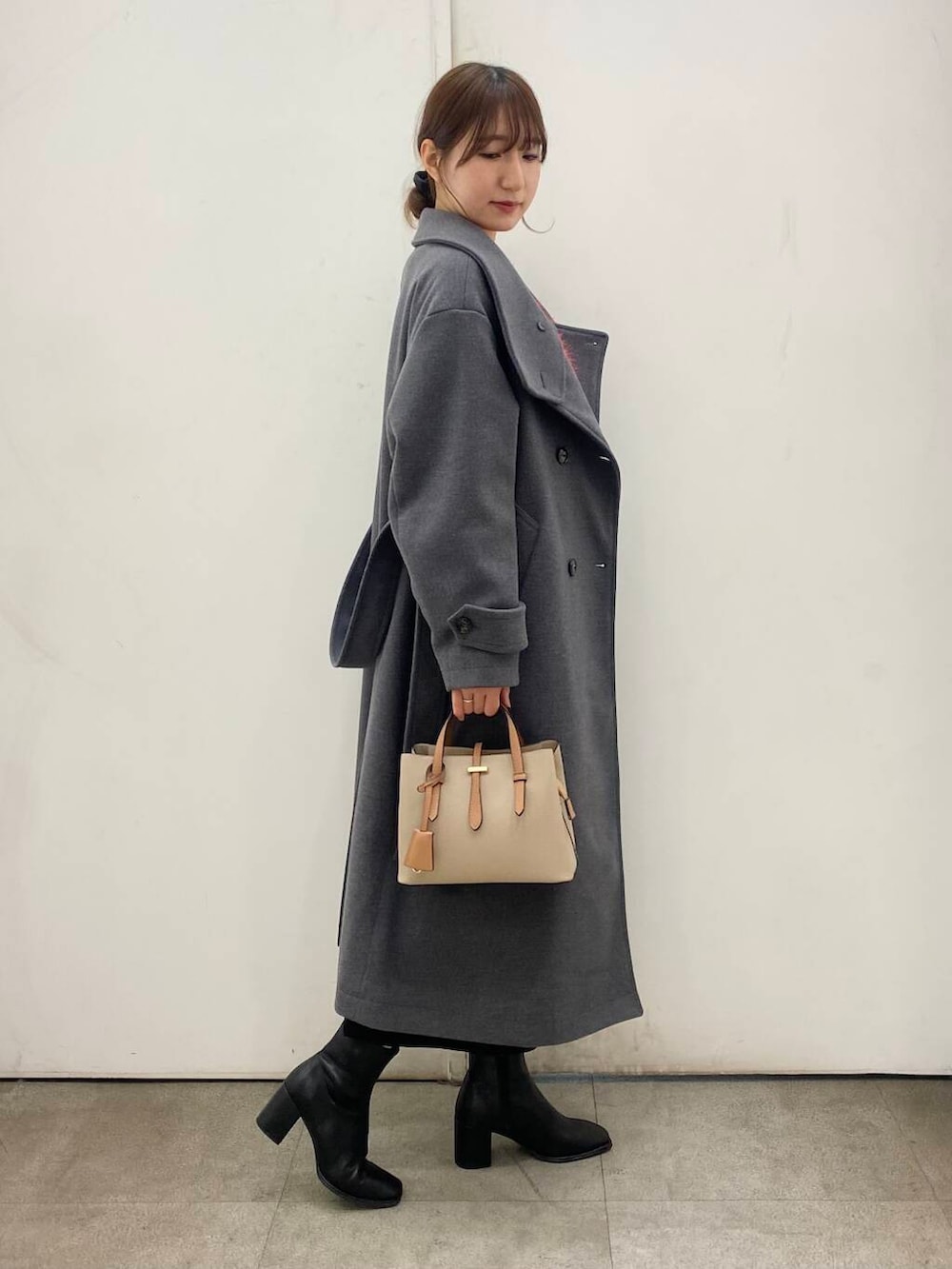 ベージュ系のハンドバッグ、ブラック系のブーツ、レッド系のニット/セーターを着用したレディースの冬コーディネートの4枚目の写真