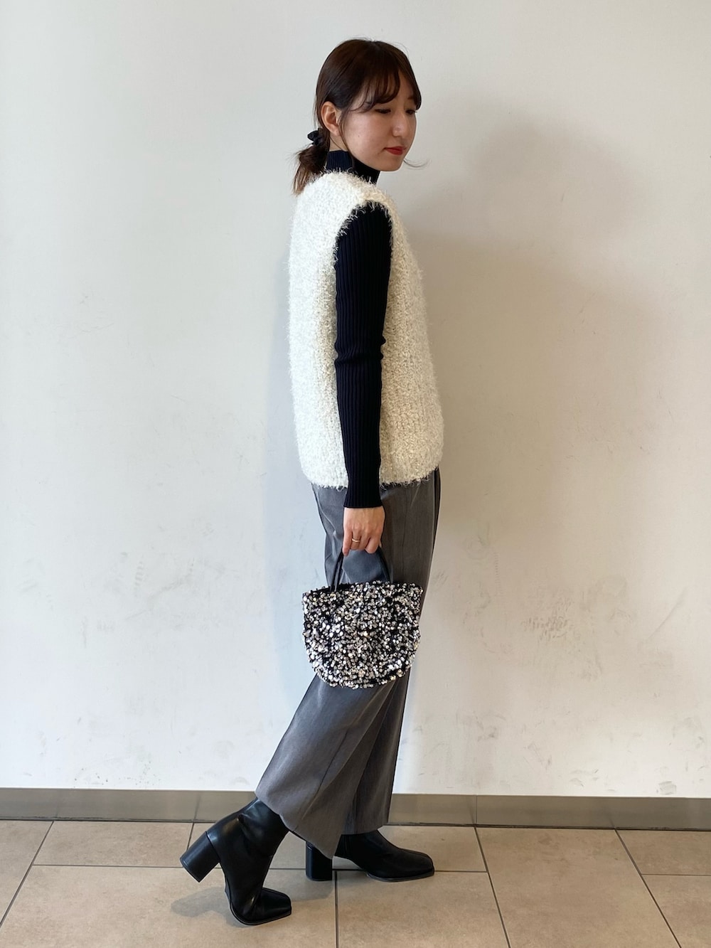 ブラック系のブーツ、グレー系のその他パンツ、シルバー系のショルダーバッグを着用したレディースの冬コーディネートの2枚目の写真