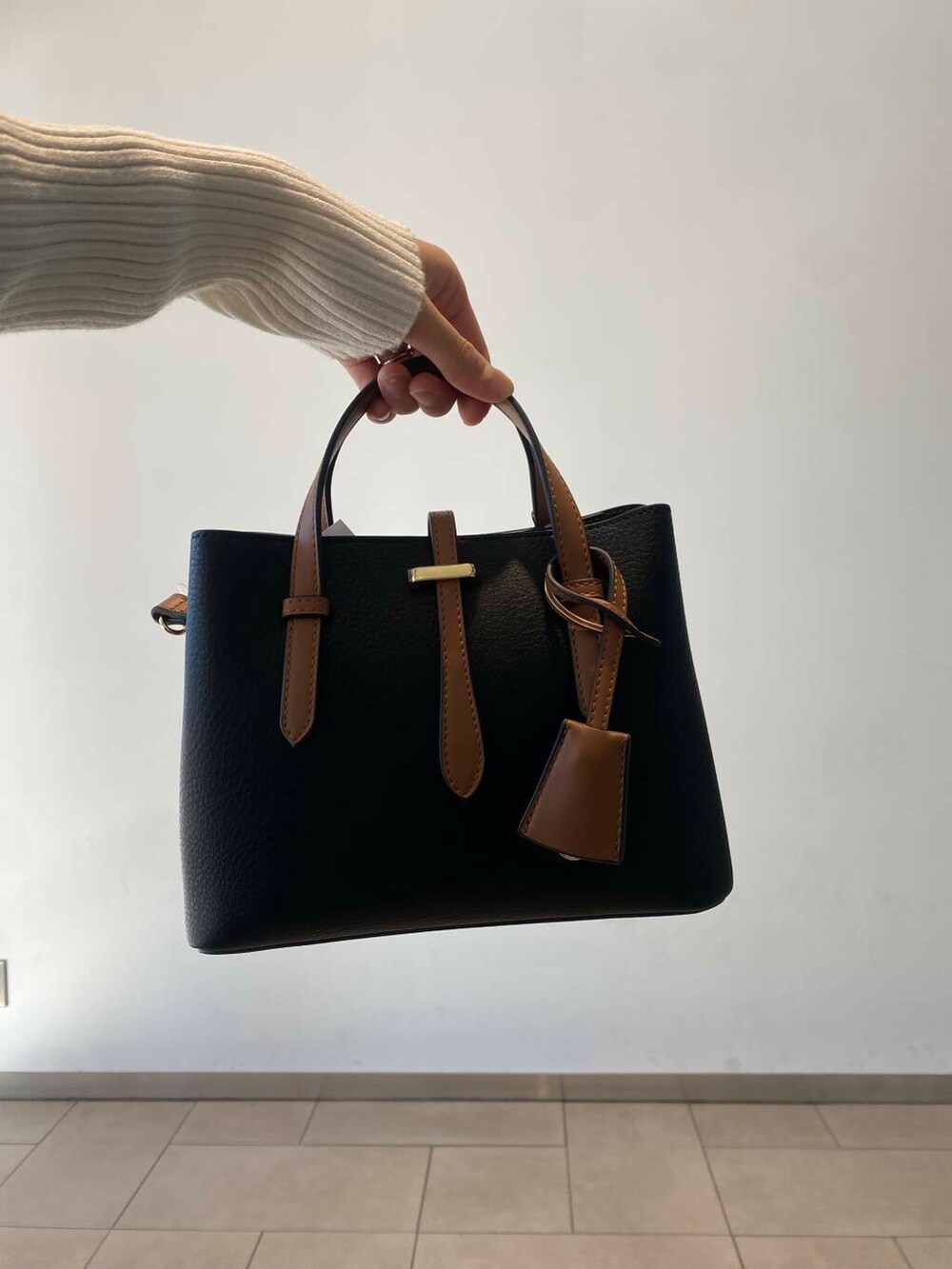 ブラック系のハンドバッグ、ホワイト系のニット/セーター、ブラック系のブーツを着用したレディースの冬コーディネートの3枚目の写真