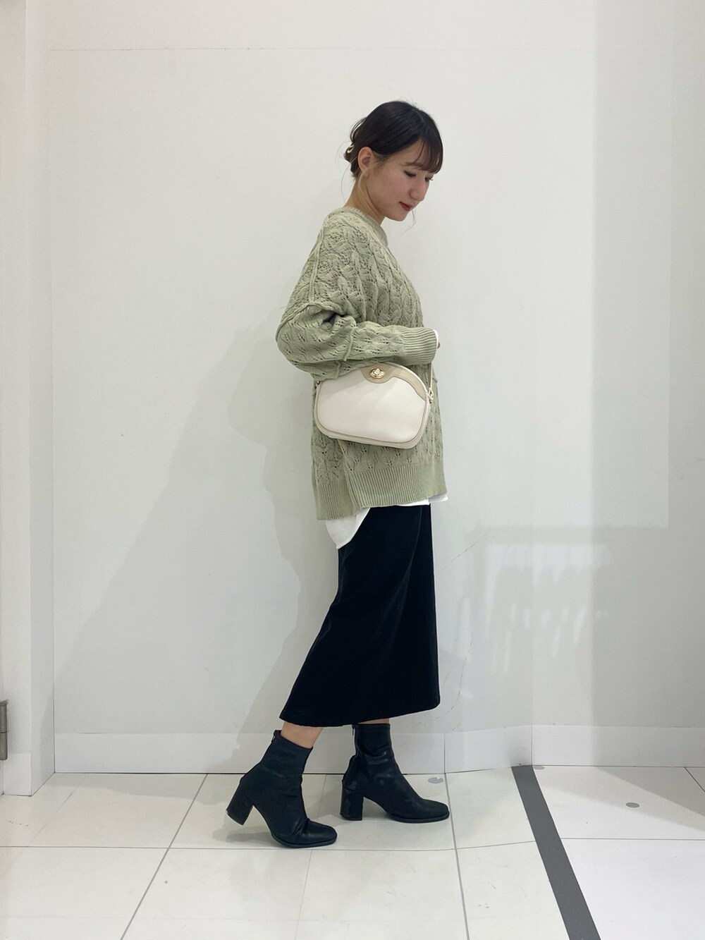 グリーン系のニット/セーター、ホワイト系のショルダーバッグ、ホワイト系のTシャツ/カットソーを着用したレディースの冬コーディネートの2枚目の写真