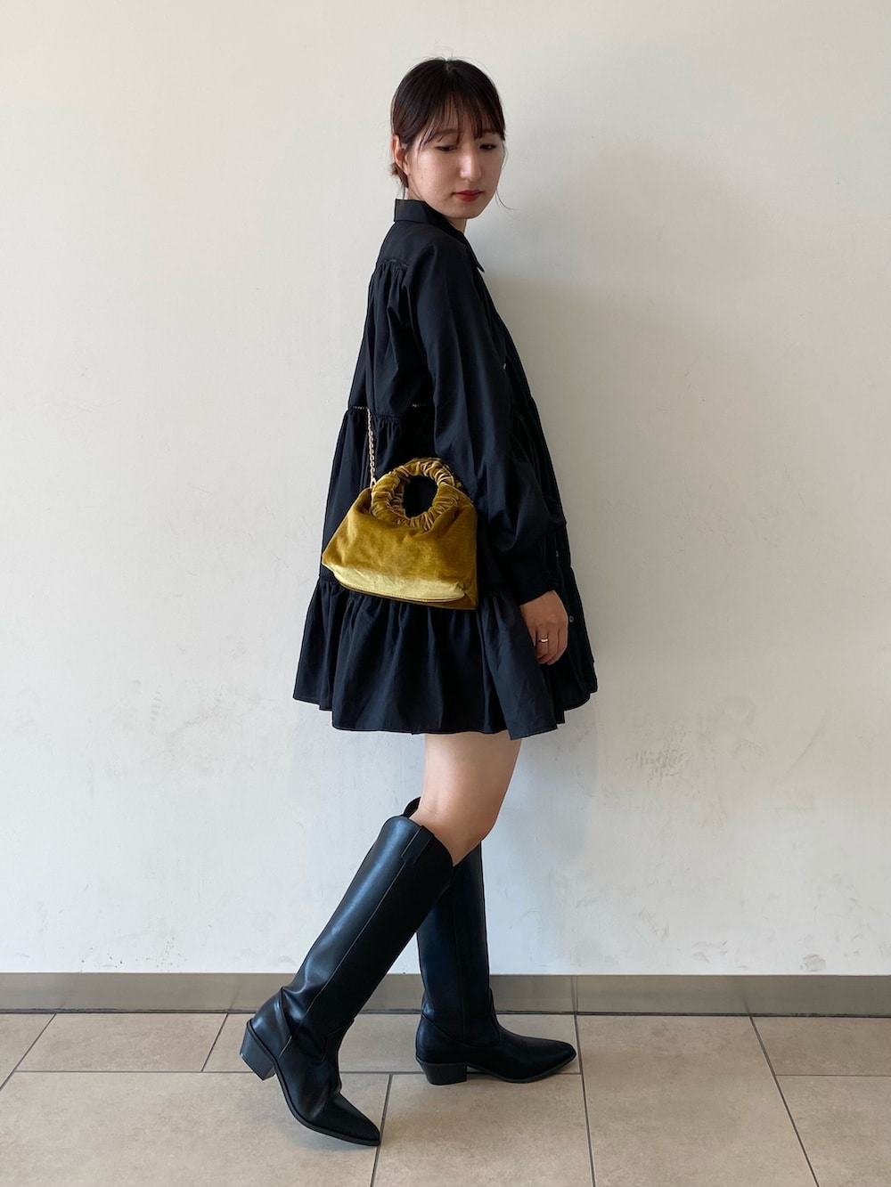 ブラック系のブーツ、ブラック系のワンピース、イエロー系のハンドバッグを着用したレディースの秋コーディネートの2枚目の写真