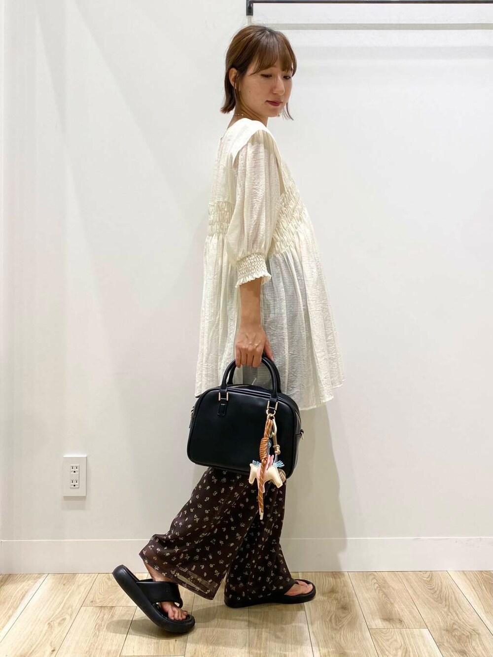 ホワイト系のワンピース、ホワイト系のタンクトップ、ブラック系のボストンバッグを着用したレディースの夏コーディネートの2枚目の写真